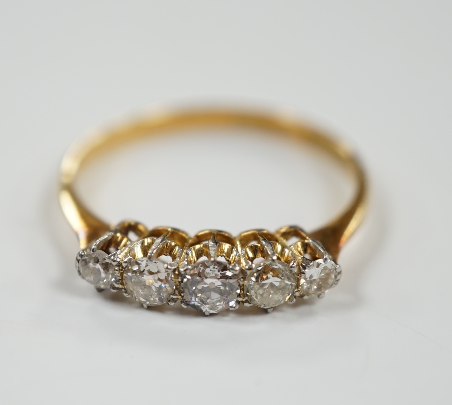 An 18ct, pt. and graduated five stone diamond set half hoop ring, size Q, gross weight 2.4 grams.